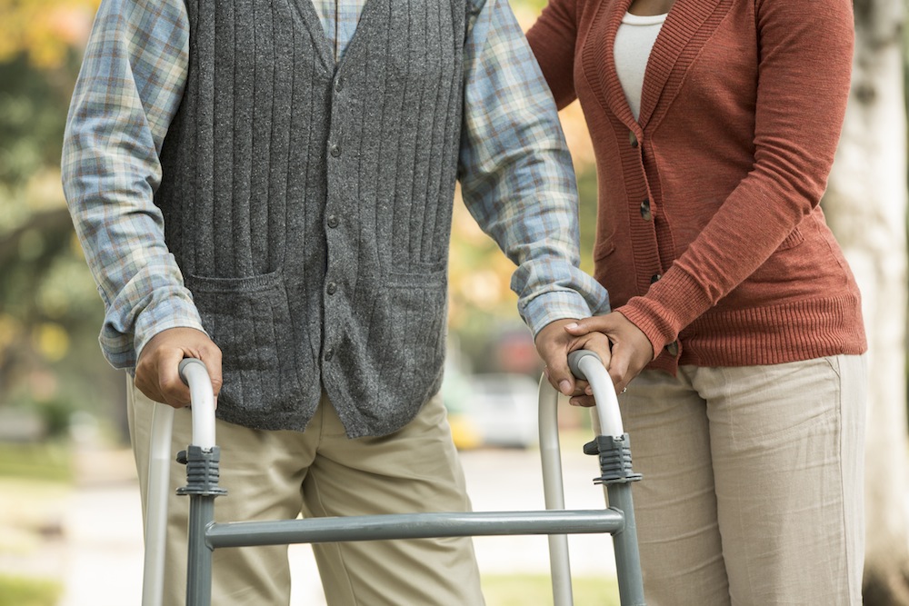 African American woman helping father use walker